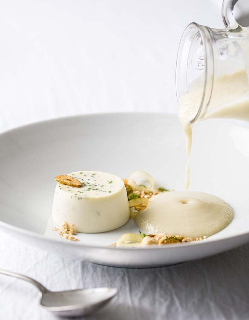 At Marcia Selden Catering, the soup is poured tableside for its fan-favorite starter Boursin Panna Cotta with Sunchoke and Roasted Garlic Soup.