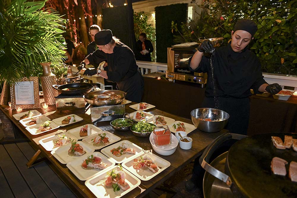 Puff ‘n Stuff Catering chefs prepare Salmon Caribbean Curry in front of guests.