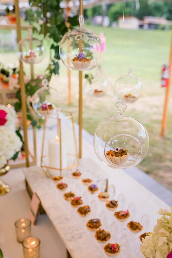 Guests select small bites from hanging glass orbs at this station by Delivering Experiences.